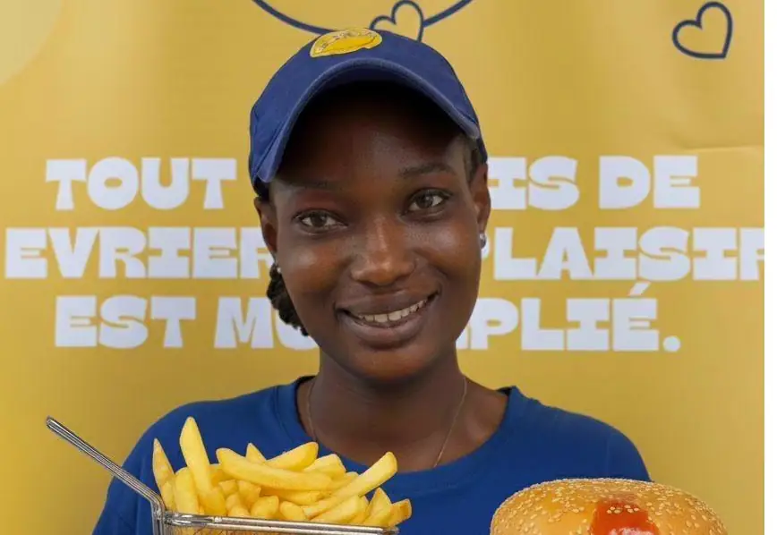 Une membre de l'équipe Shawar'Mama présentant un burger et des frites