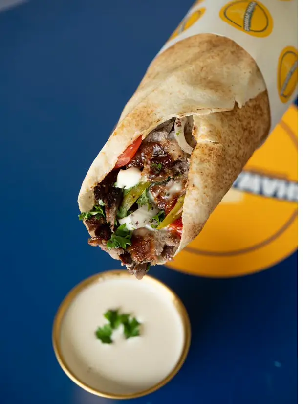 Sandwich shawarma bœuf trempé dans la sauce à l'ail